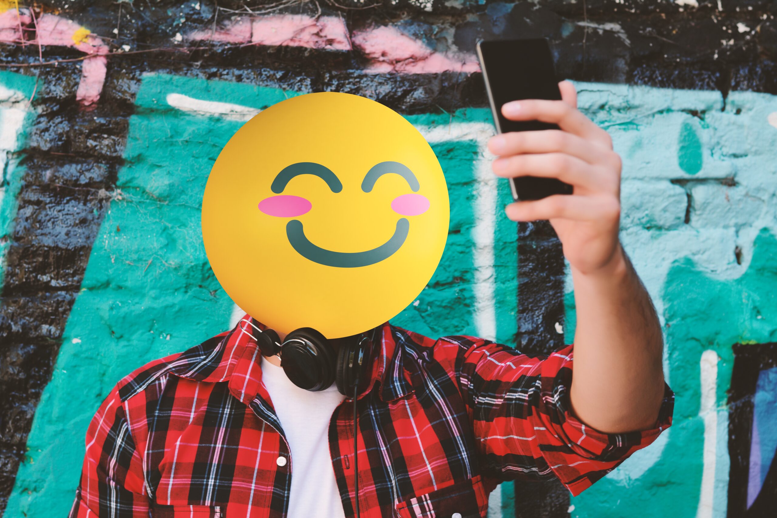 Person taking a selfie with an emoji smiling face as a head