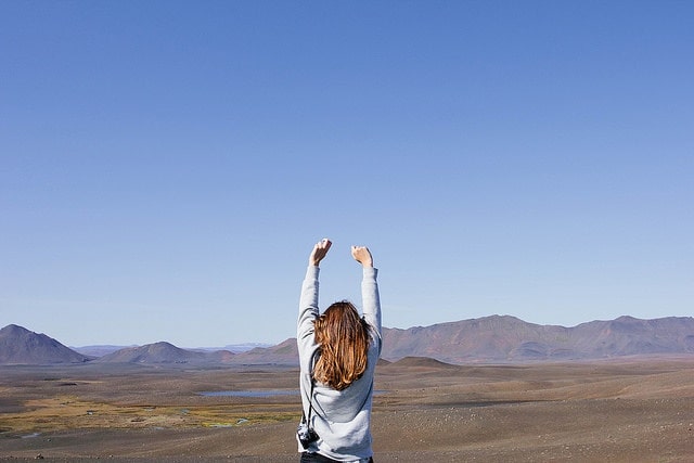 Girl with hands over head overlooking nice landscape