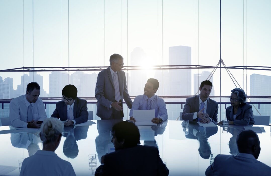 Business people sitting around a conference table with a skyline at sunset in the background