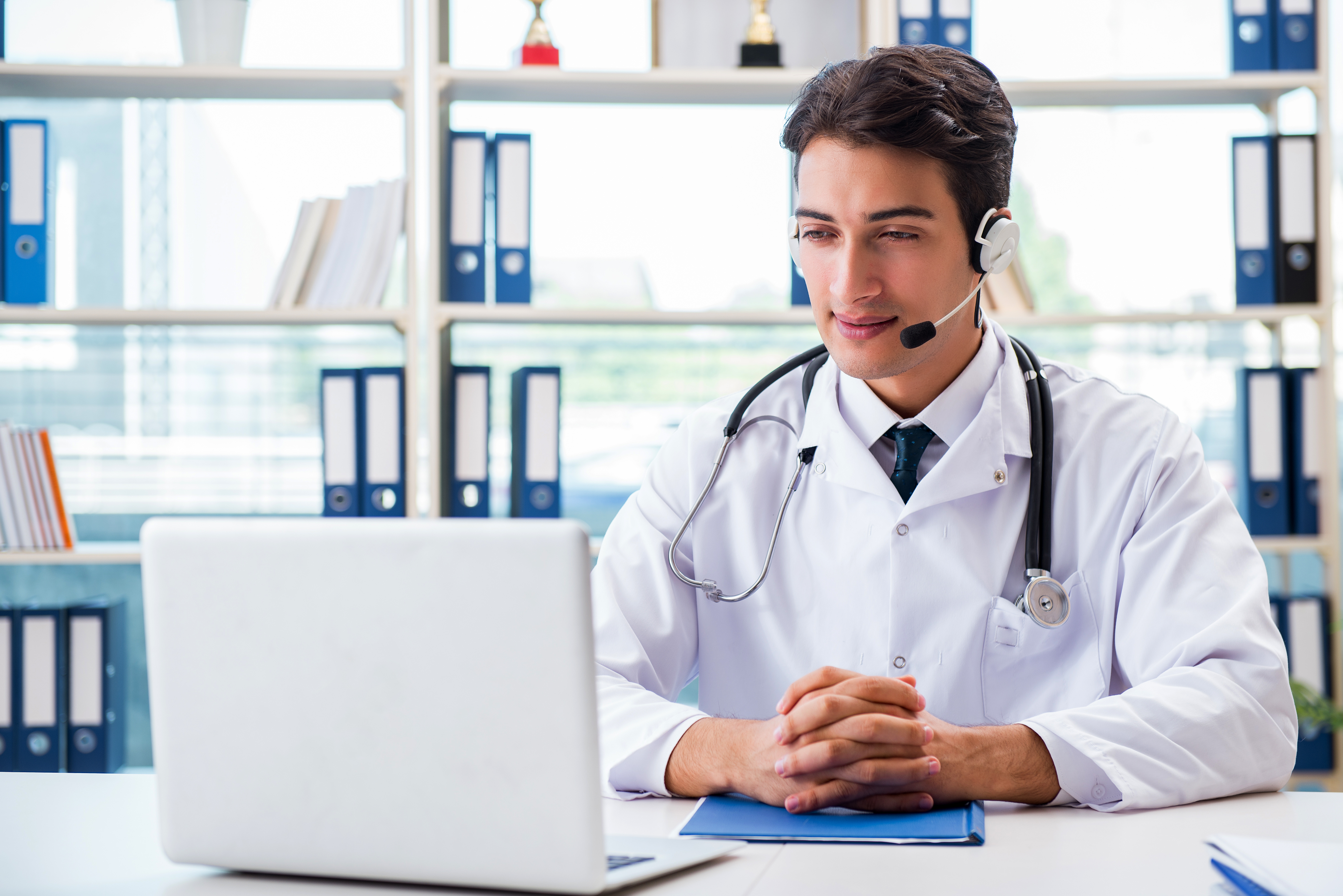 a doctor uses his laptop to conduct a telehealth visit