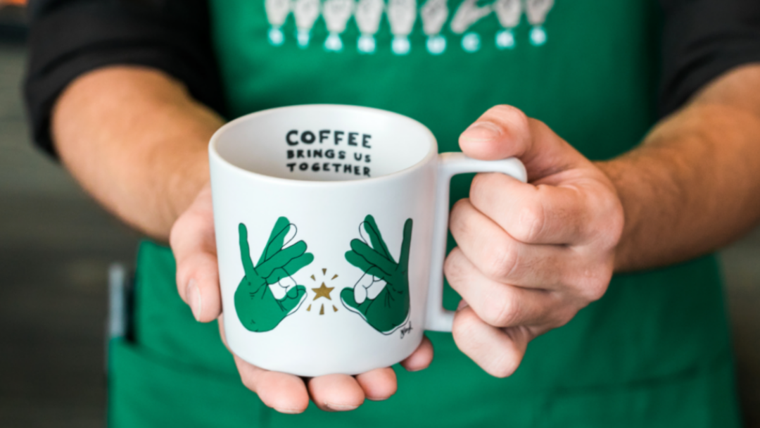 person holding a coffee mug with sign language on it